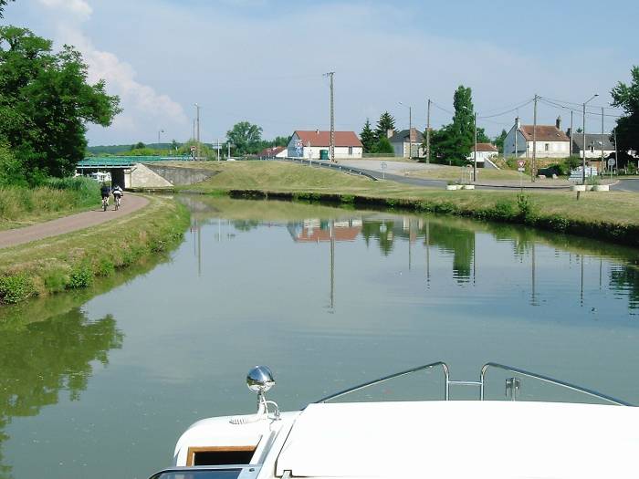 People walking and riding bicycles on a canal bank in central France