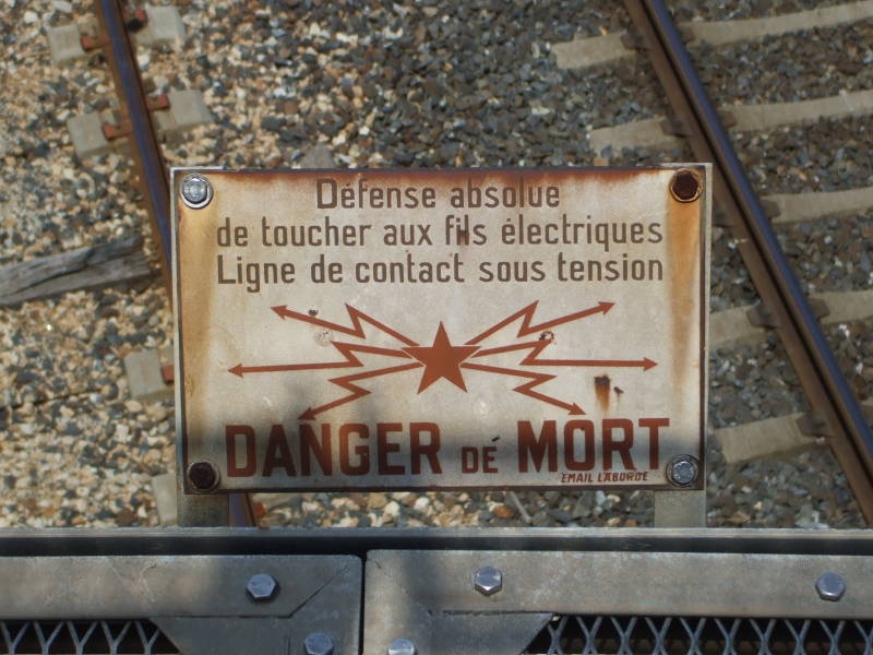 Warning sign: Defense absolue de toucher aux fils electriques. / Ligne de contact sous tension. / Danger de Mort