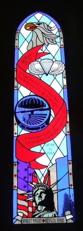 Stained glass window commemorating D-Day in the church at Angoville au Plain, in Normandy.  U.S. eagle, U.S. paratrooper emblems, U.S. and French flags, and the text of John 15:13 -- Il n'ya pas de plus grand amour que de donner sa vie pour ses amis. Greater love has no one than this, that he lay down his life for his friend.