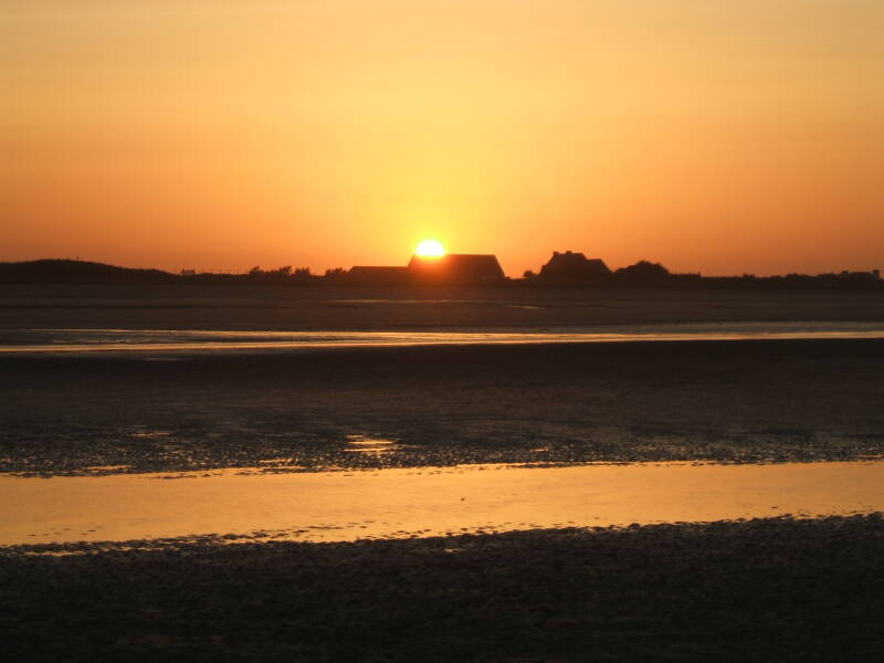 Sunset over Utah Beach. A few large Norman farm houses.