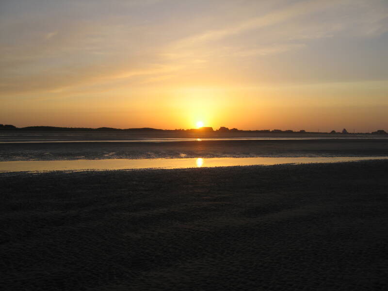 Sunset over Utah Beach. Large Norman farm houses in the distance.