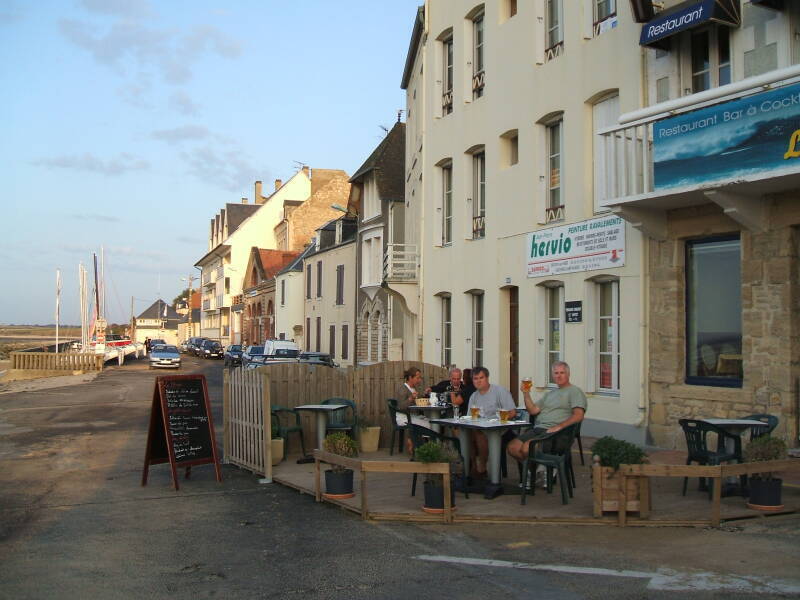 Three men drinking beer at an outdoor cafe in France.