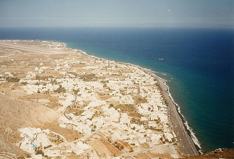 View down from Moni Profiti Ilia, an airliner on final approach is seen from above.