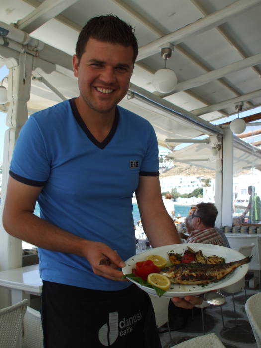 Waiter with grilled fish on the Greek island of Mykonos.