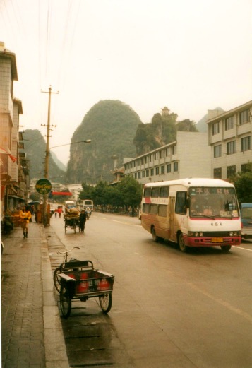 Minibus, cargo bicycle, and motorized cargo bike on the highway through Yangshuo, China.