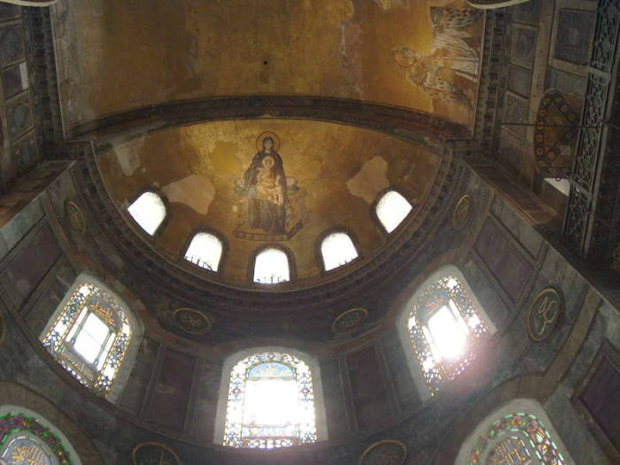 Interior of the Hagia Sophia or Aya Sofya, in Istanbul. Mosaic of the Virgin Mary and Jesus in a large semi-dome, stained glass windows below.