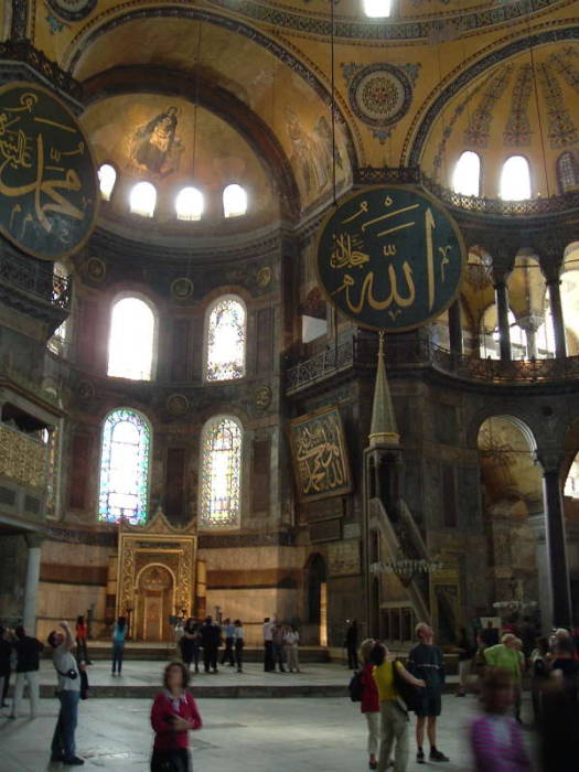 Interior of the Hagia Sophia or Aya Sofya, in Istanbul. Mosaic of the Virgin Mary and Jesus in a large semi-dome over the altar area. Mihrab showing the direction to Mecca. Minbar or pulpit from which the Imam delivers the sermon. Large medallions with Koranic quotes in large calligraphy.