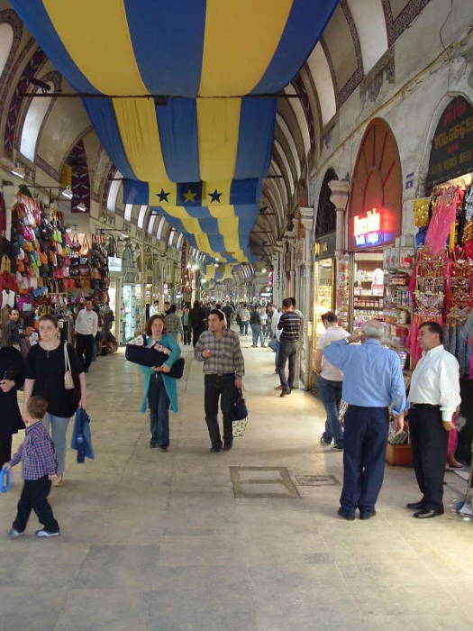Interior of the Grand Bazaar in Istanbul. Indoor street lined with shops, stone archways and domes.