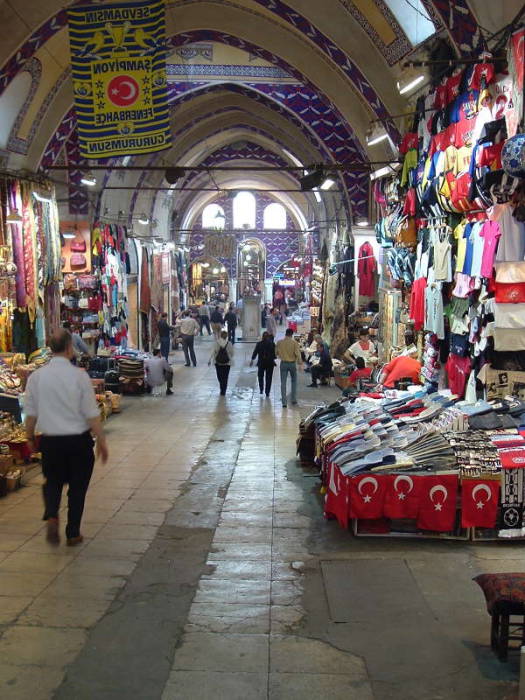 Interior of the Grand Bazaar in Istanbul. Indoor street lined with shops, stone archways and domes.