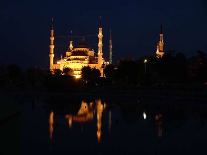 Blue mosque or Sultanahmet Cami, in Istanbul, with its six minarets and many domes. Nighttime view with reflecting pool.