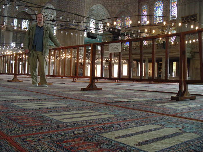 Interior of the Blue mosque or Sultanahmet Cami, in Istanbul. Mihrab and Minbar. Large chandeliers above many prayer rugs.