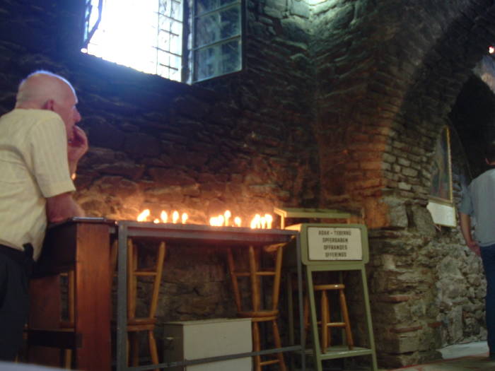 Prayer inside the Virgin Mary's house at Maryemana Evi. A row of candles.
Stone walls.