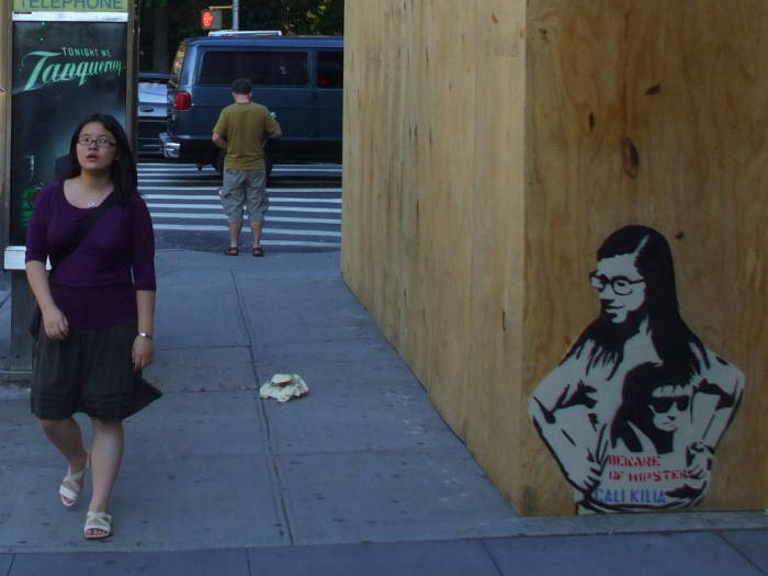 Hipster girl walking past stencil art of a hipster girl wearing a T-shirt bearing stencil art. BEWARE OF HIPSTERS!