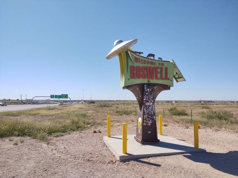 'Welcome to Roswell' sign with spacecraft lifting cattle.
